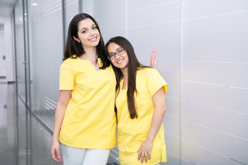 Zwei ZFAs im Gang der Praxis lachen in die Kamera