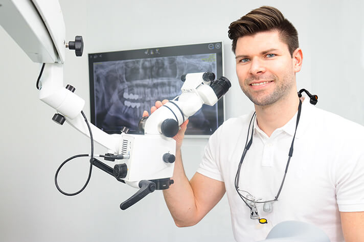 Zahnarzt sitzt am Mikroskop