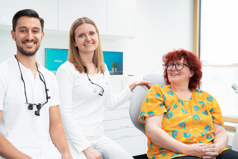 Zahnärzte zusammen mit einer zufriedenen Patientin