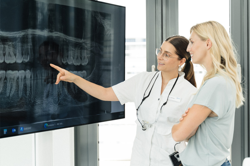 Zahnärztin und Patientin besprechen ein Röntgenbild am Screen